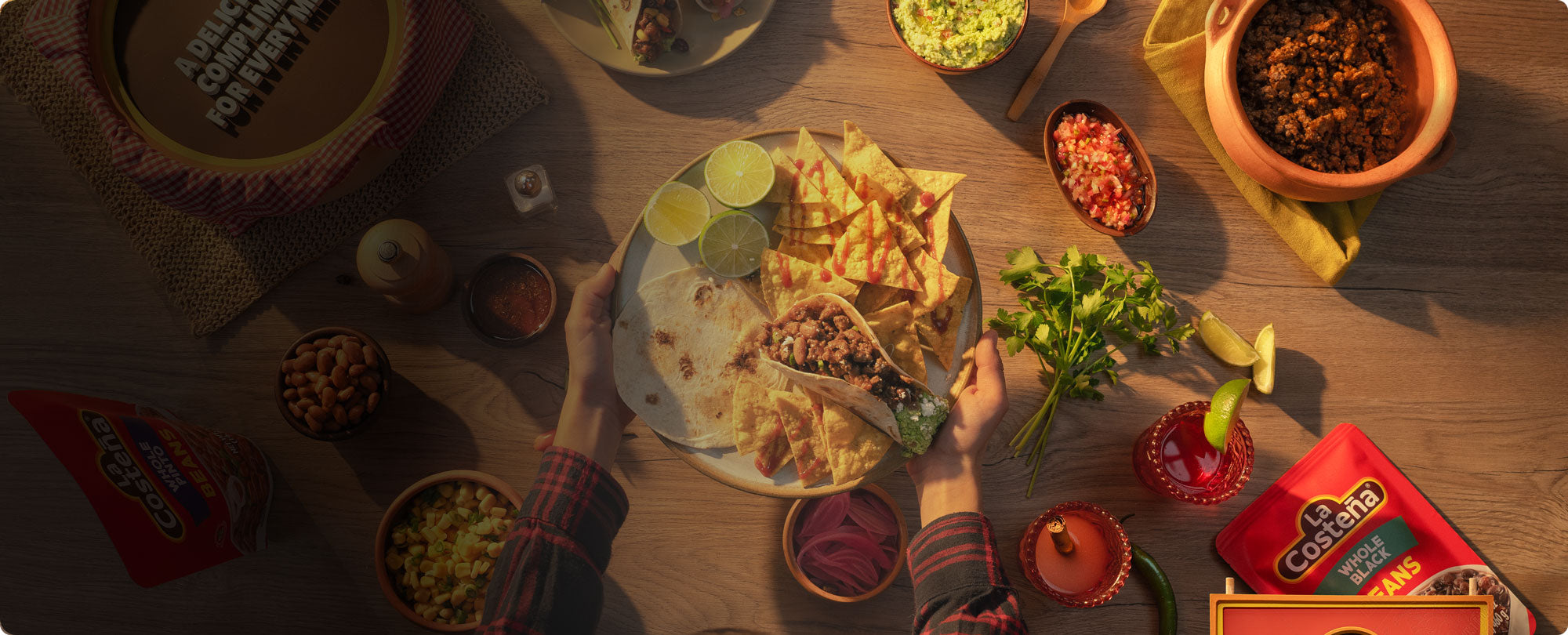 La Costeña meal with tacos, tortilla chips, lime, salsa, and fresh herbs
